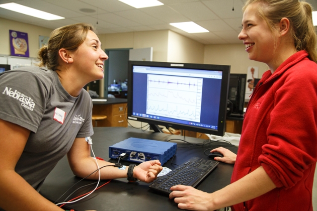 A student wearing a medical device smiles while talking to another student. 